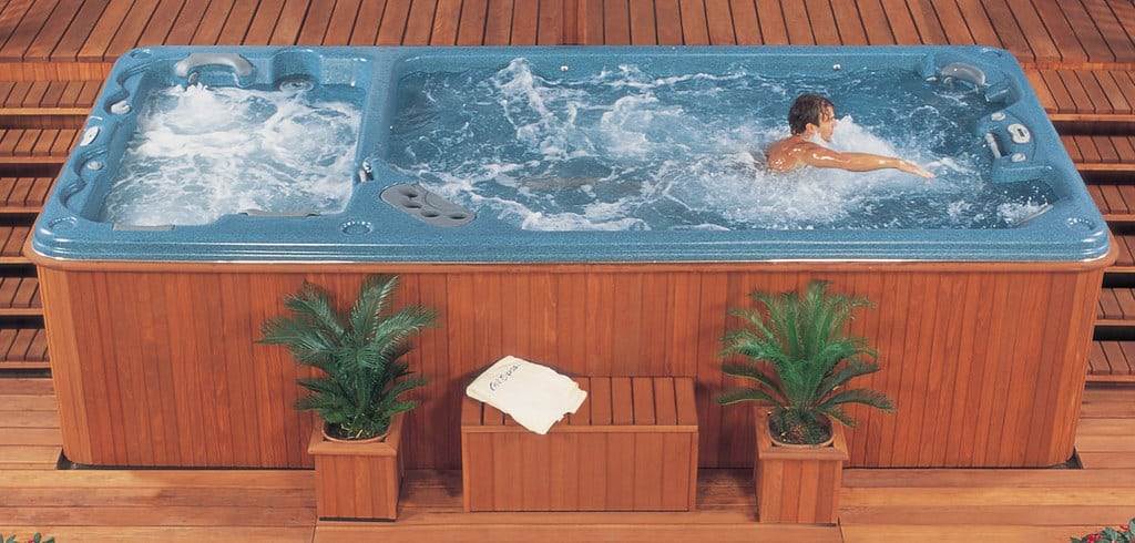 Vintage Cal Swim Spa with brown cabinet and blue acrylic shell showing a man swimming in the swim feature