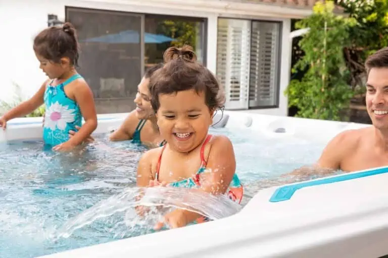 Three young girls playing together in an Endless Pool on a sunny day, showcasing a clean, scum-free hot tub, and demonstrating how to eliminate scum in hot tubs.