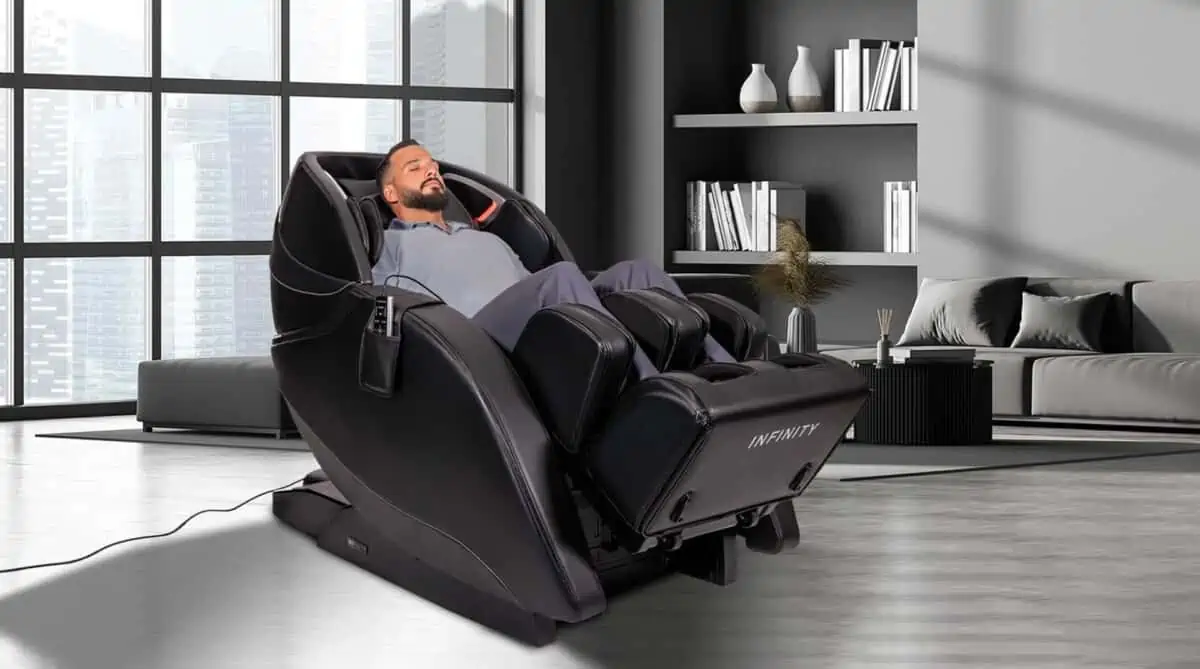 A relaxed man enjoying the benefits of a massage chair in a modern home, with a bookshelf on one side and a city skyline visible in the background.