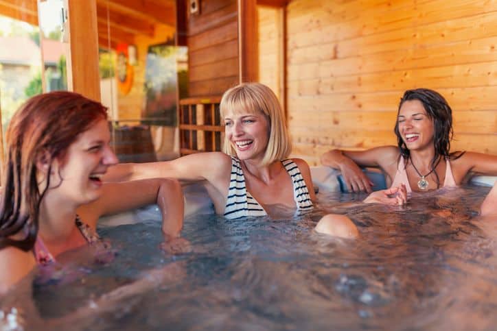 three women in a hot tub laughing