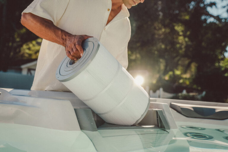 67 Hot Tub Tips Only Spa Experts Know - Take A Break Spas And Billiards Blog Man Replacing A Sundance Spa Filter With Trees And Sunset In The Background