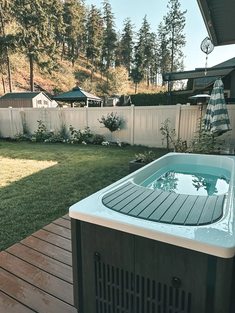 Brown and white Kodiak Cold Plunge filled with water in a Utah backyard with grass and a deck in the background